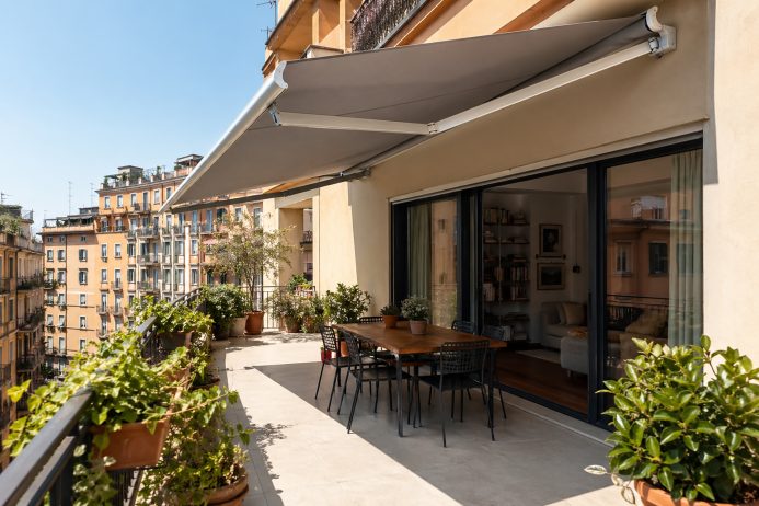 Terrazza con tende da sole e tavolo da pranzo sotto ombra.